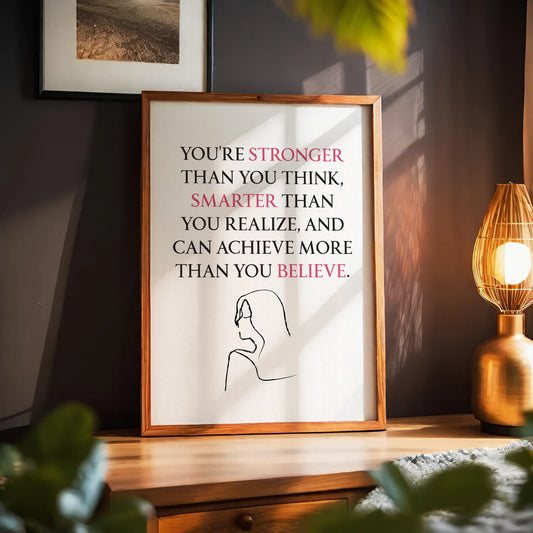 Empowering printable wall art featuring the quote 'You're stronger than you think, smarter than you realize, and can achieve more than you believe' with key words highlighted in pink, paired with a minimalist line drawing of a woman, perfect for confidence-boosting modern decor.