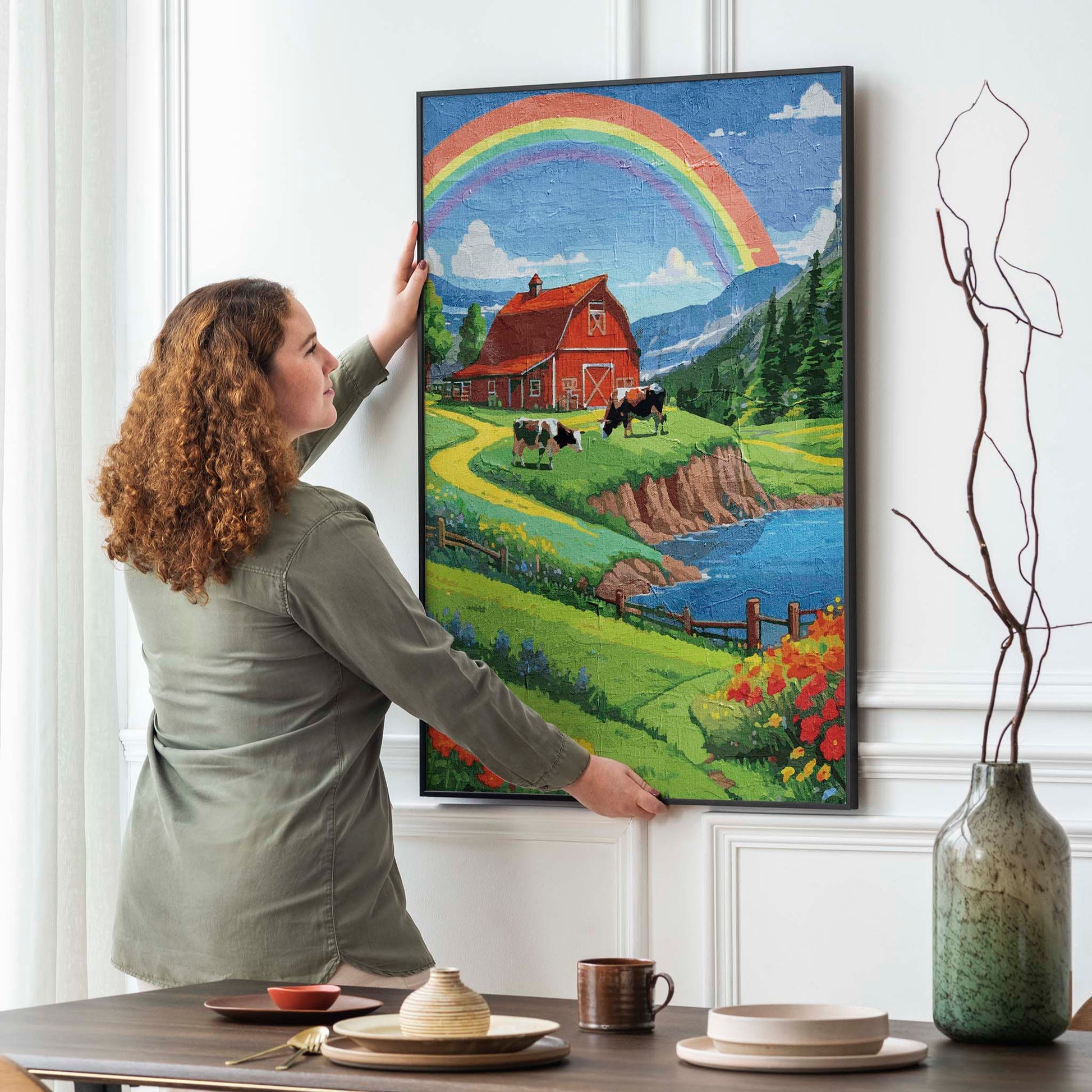 Charming countryside printable wall art featuring a vibrant red barn, grazing cows, colorful wildflowers, and a winding path beside a sparkling lake, all under a bright rainbow arching across a blue sky - perfect for farmhouse, cottagecore, or rural-themed decor