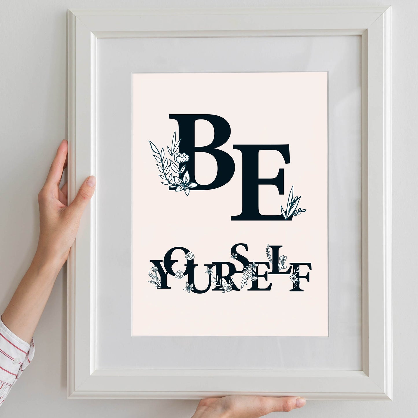 Aesthetic floral-themed printable wall art featuring the motivational phrase 'Be Yourself' in bold black serif typography decorated with delicate botanical illustrations, set against a soft beige background with natural light - ideal for bedroom, dorm, or creative space decor