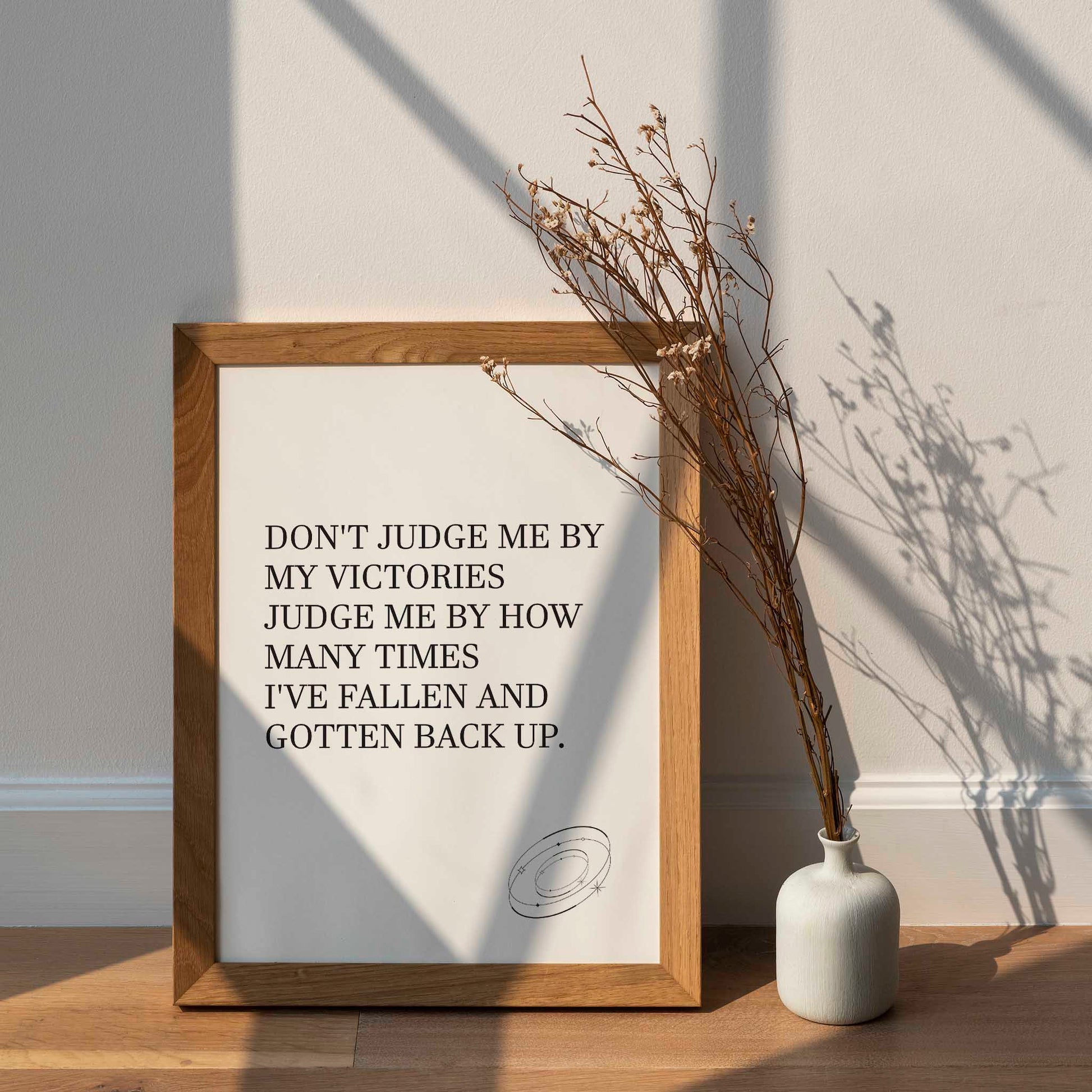 Inspirational printable wall art featuring the empowering quote 'Don't judge me by my victories, judge me by how many times I've fallen and gotten back up' in classic serif font, with a small sketched ring accent, perfect for resilience-themed or motivational spaces.