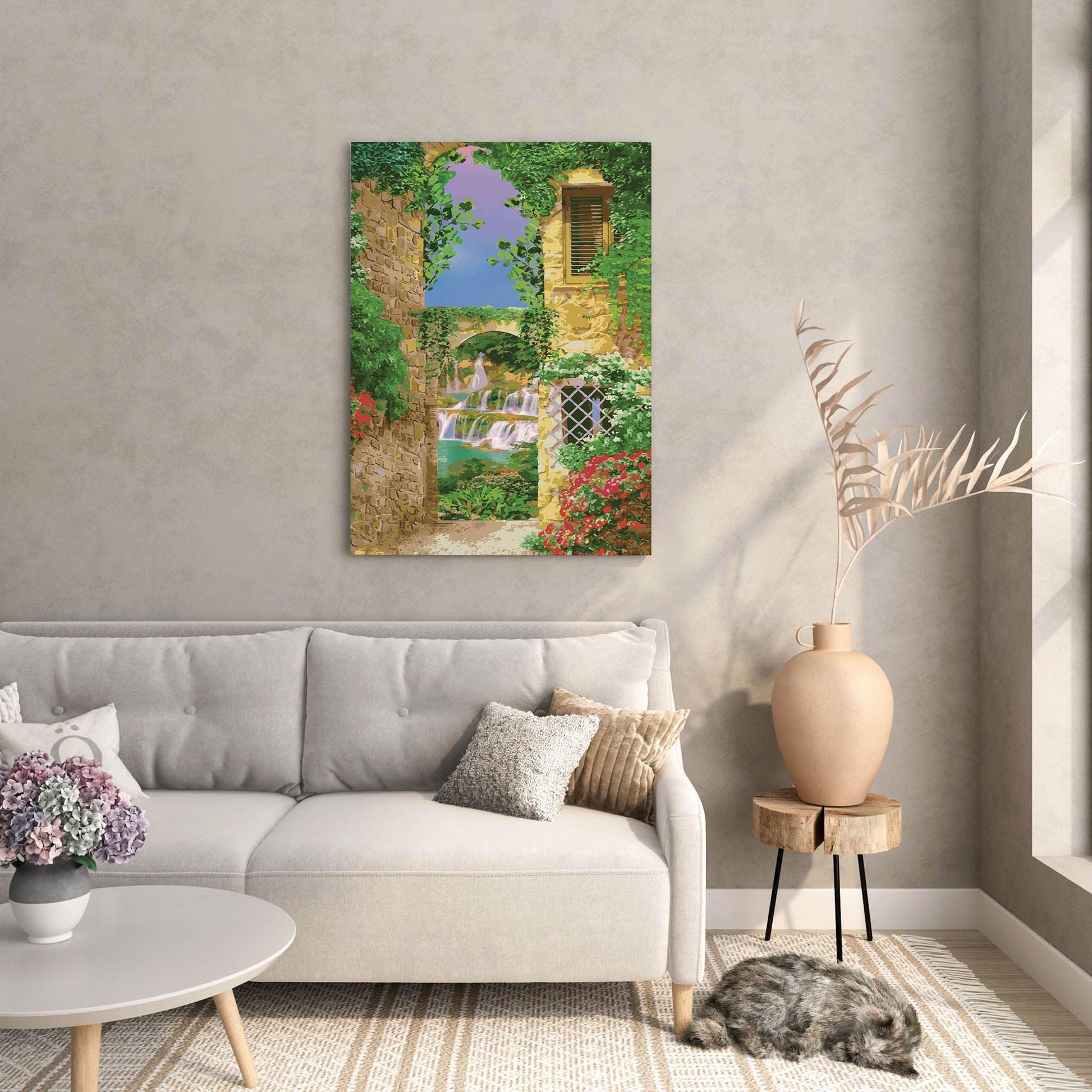 Charming printable wall art of a Mediterranean alleyway framed by ivy-covered stone buildings, with a view of cascading waterfalls and a stone bridge under a vibrant purple-blue sky, perfect for bringing a touch of European romance to your space