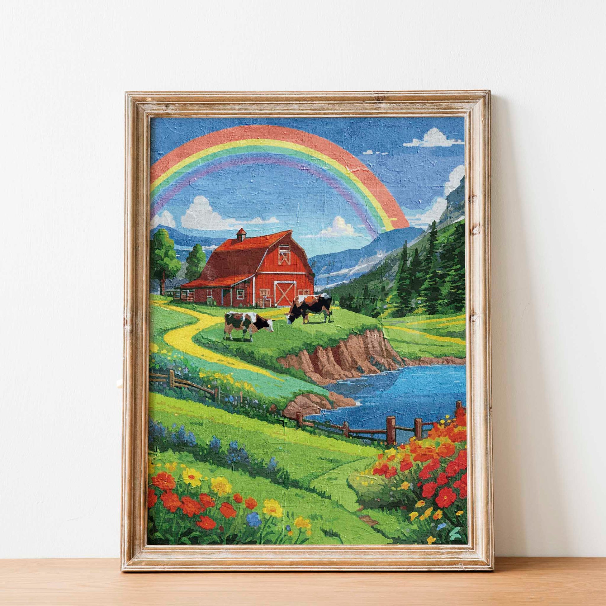 Charming countryside printable wall art featuring a vibrant red barn, grazing cows, colorful wildflowers, and a winding path beside a sparkling lake, all under a bright rainbow arching across a blue sky - perfect for farmhouse, cottagecore, or rural-themed decor