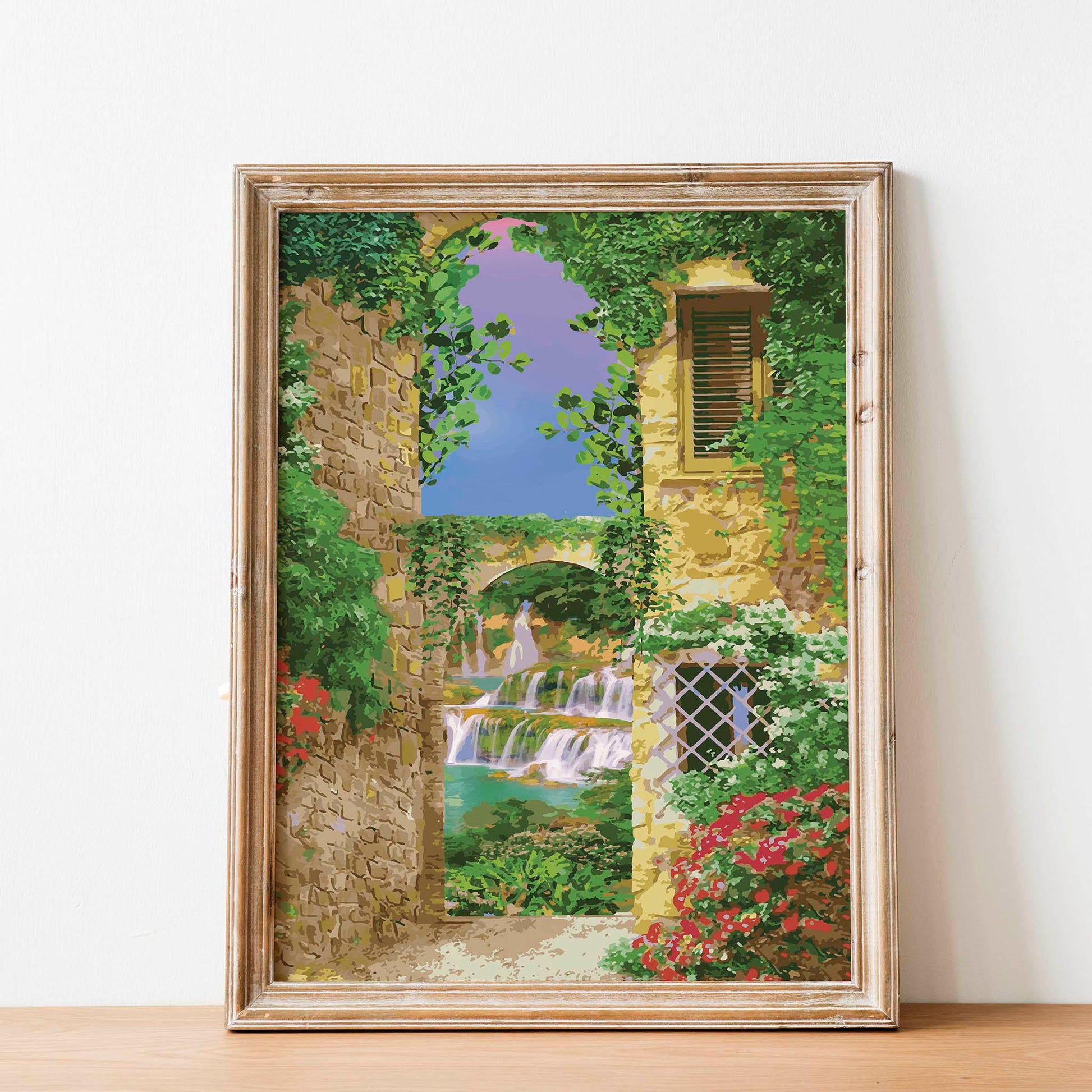 Charming printable wall art of a Mediterranean alleyway framed by ivy-covered stone buildings, with a view of cascading waterfalls and a stone bridge under a vibrant purple-blue sky, perfect for bringing a touch of European romance to your space