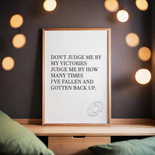 Inspirational printable wall art featuring the empowering quote 'Don't judge me by my victories, judge me by how many times I've fallen and gotten back up' in classic serif font, with a small sketched ring accent, perfect for resilience-themed or motivational spaces.