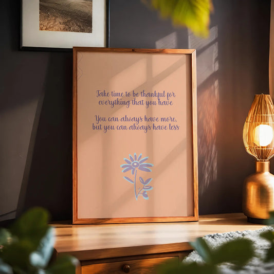 Gratitude-themed printable wall art featuring the quote 'Take time to be thankful for everything that you have. You can always have more, but you can always have less' in elegant purple script on a warm peach background, accented with a whimsical lavender and blue flower illustration, perfect for cozy home, mindfulness, or wellness decor