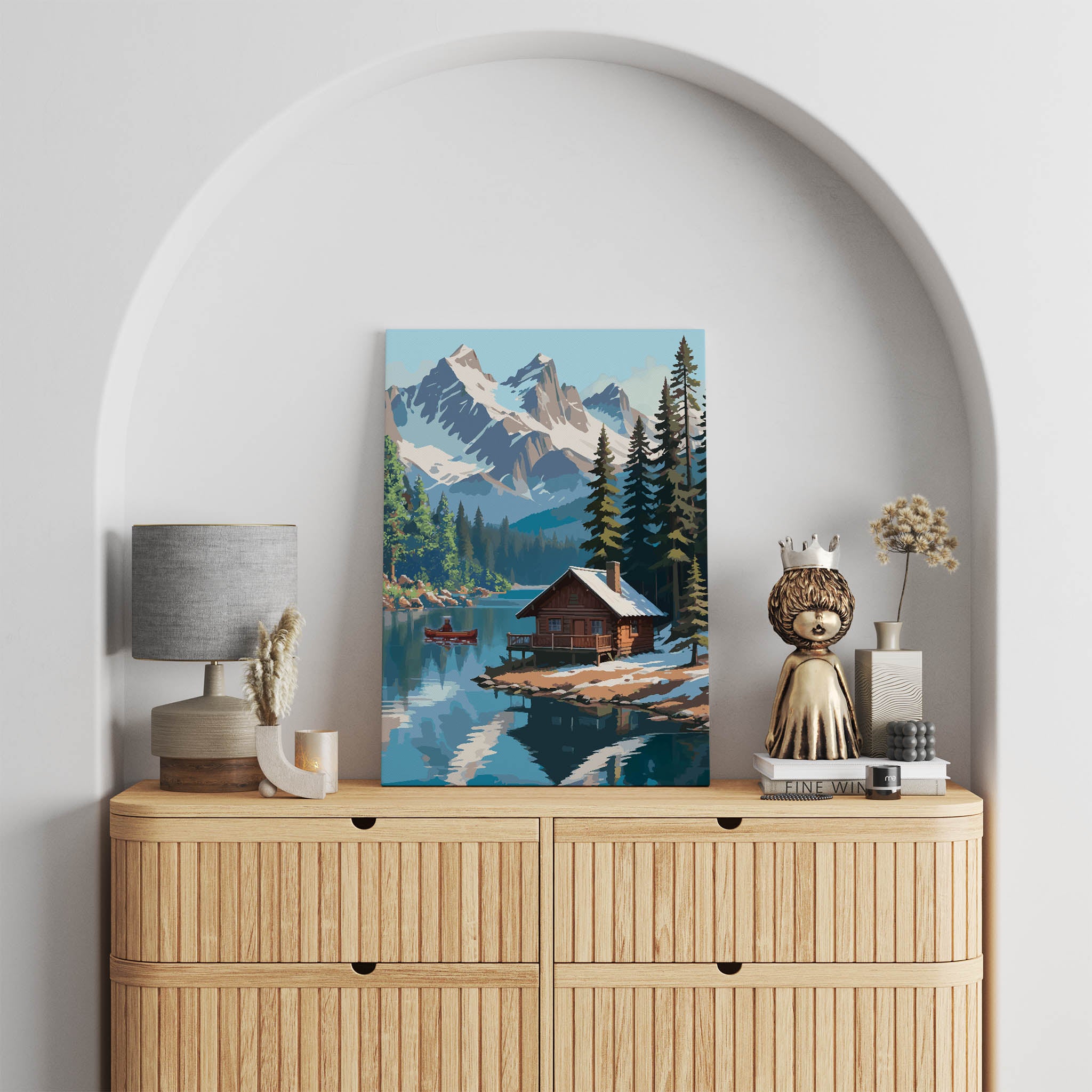 Rustic winter cabin printable wall art featuring a cozy log cabin on the edge of a tranquil lake, surrounded by snow-dusted pine trees and dramatic snow-covered mountain peaks, with a red canoe gliding across the water, perfect for cabin, adventure, or nature-inspired decor