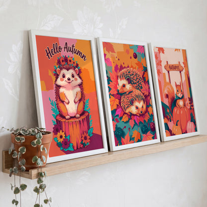 Woodland animal art bundle - three white-framed dopamine-style prints on a natural oak ledge featuring two hedgehog illustrations and a squirrel autumn scene in warm orange, pink, and teal