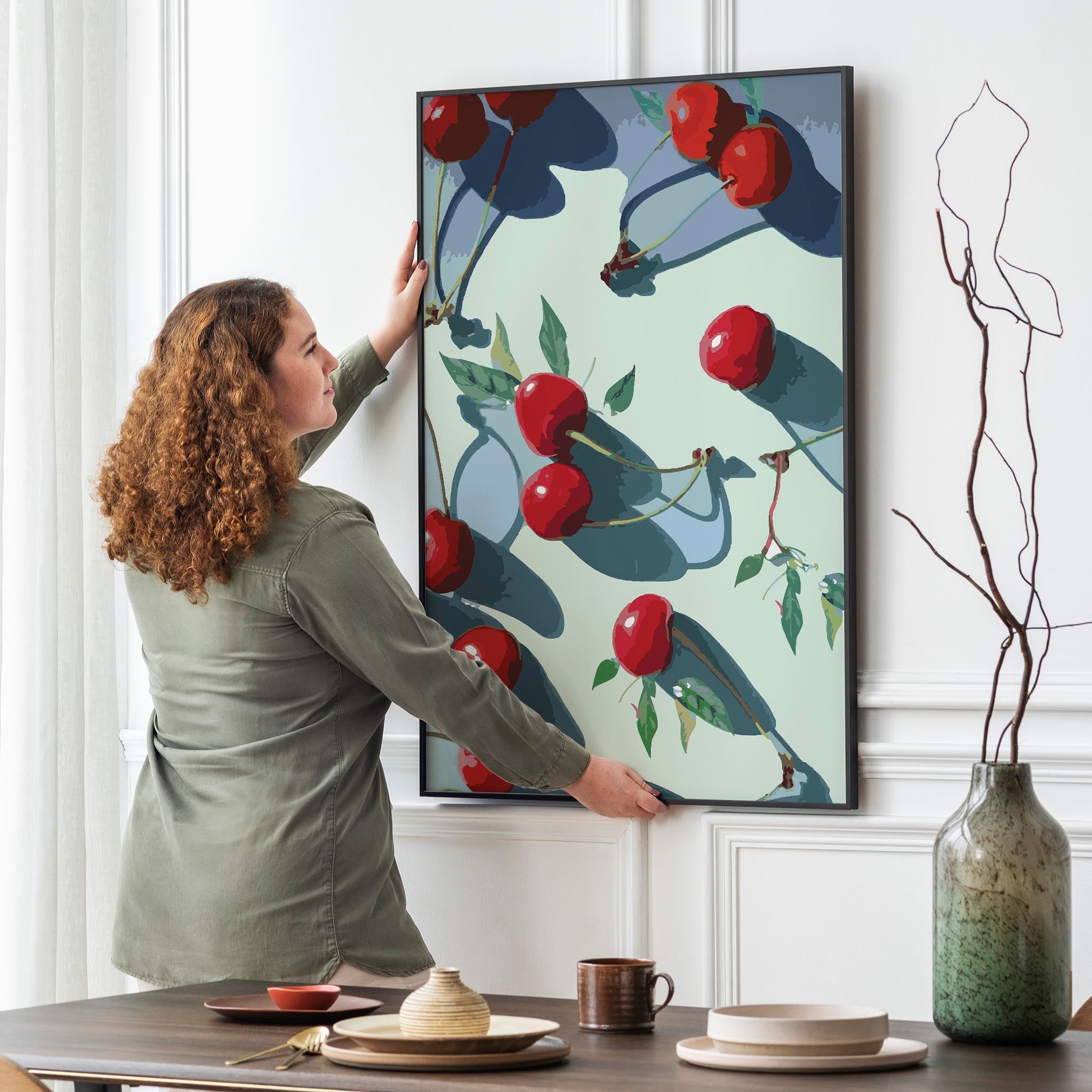 Vibrant printable wall art of glossy red cherries with green leaves casting dramatic shadows on a pale background, bold, modern kitchen or dining room decor