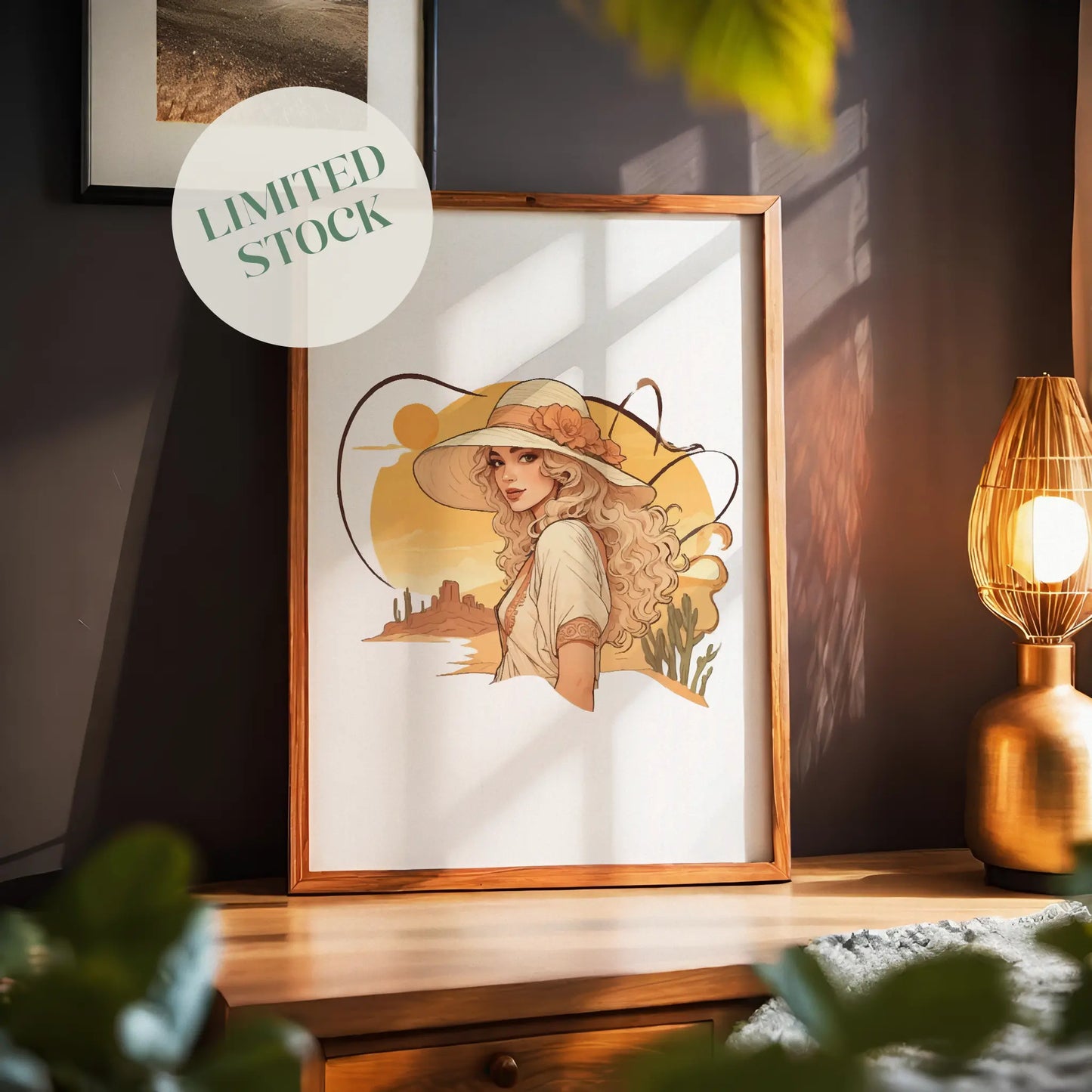 Boho-style digital wall art of a woman with flowing blonde hair wearing a wide-brimmed hat adorned with a flower, set against a warm desert sunset with cacti and mesas