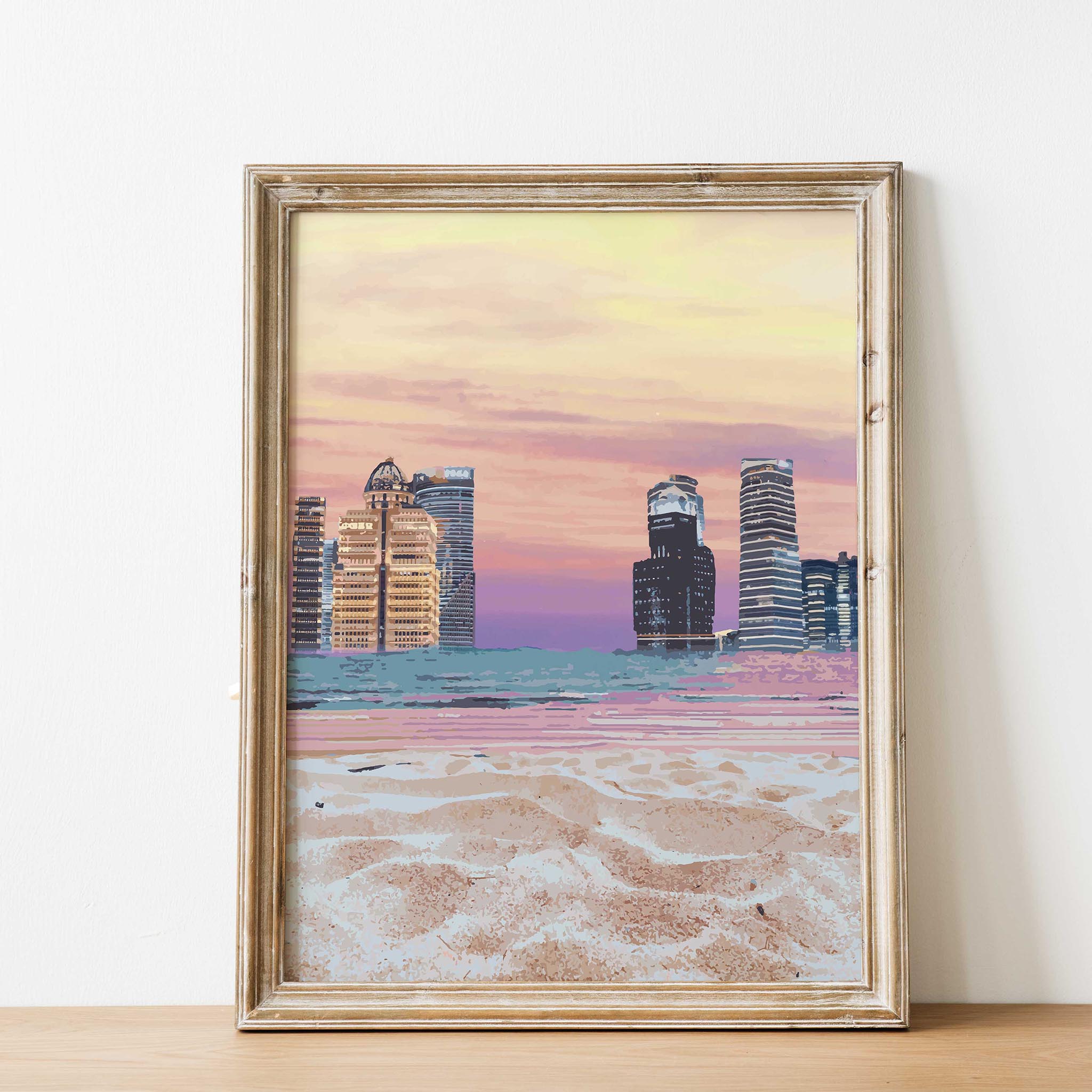 Modern cityscape wall art featuring futuristic skyscrapers along a beach shoreline, with soft sand in the foreground and a vibrant pastel sunset sky blending shades of pink, orange, and purple