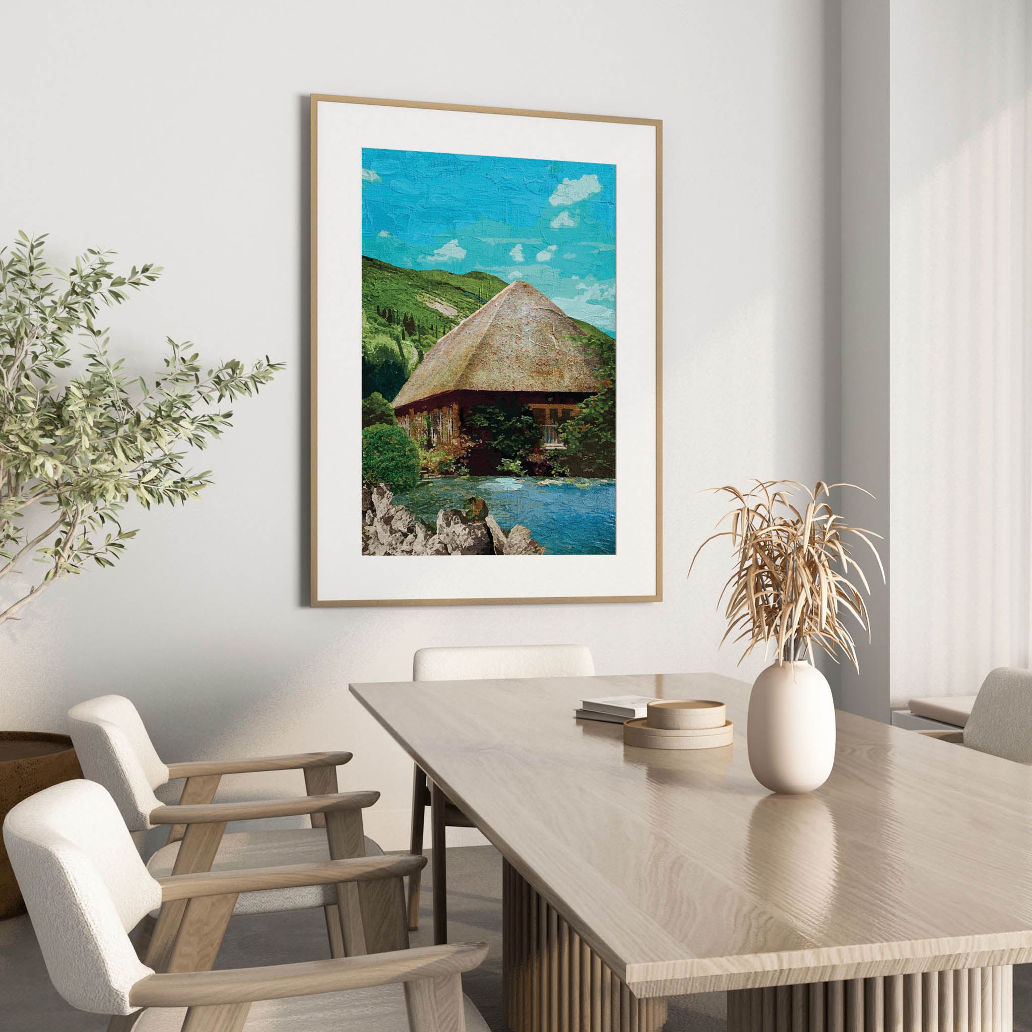 Rustic cottage wall art featuring a charming thatched-roof house surrounded by lush greenery and nestled beside a peaceful pond, with rolling green hills and a bright blue sky in the background