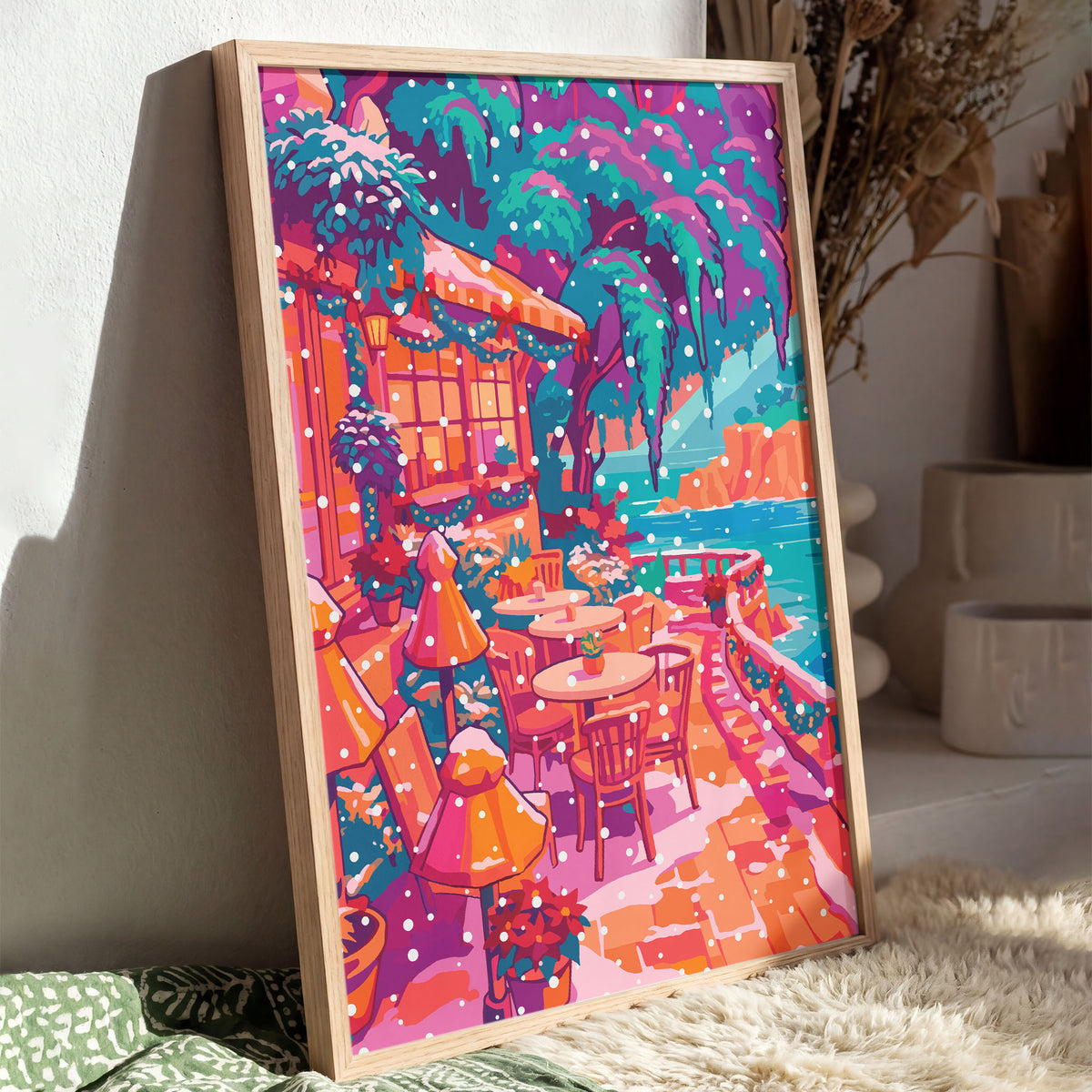 Colorful coastal wall art featuring a seaside patio with garland-draped windows, falling snow, and frosted trees above the water.