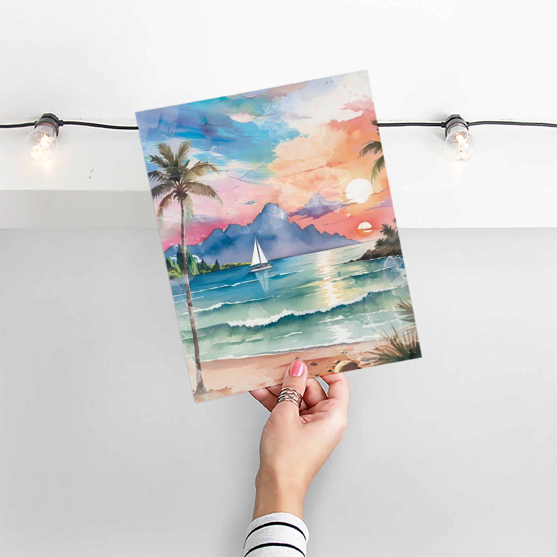 Watercolor-style printable wall art of a tropical beach sunset with palm trees, ocean waves, a sailboat, and mountains in the distance under a colorful sky