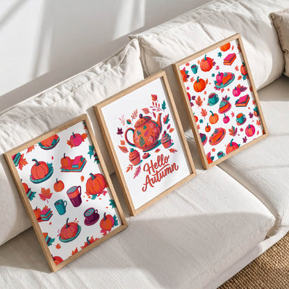 Styled shelf display of three framed cozy autumn prints in white frames on a warm oak ledge - bold orange and pink fall pattern art and a "Hello Autumn" teapot poster against a sage wainscoting wall