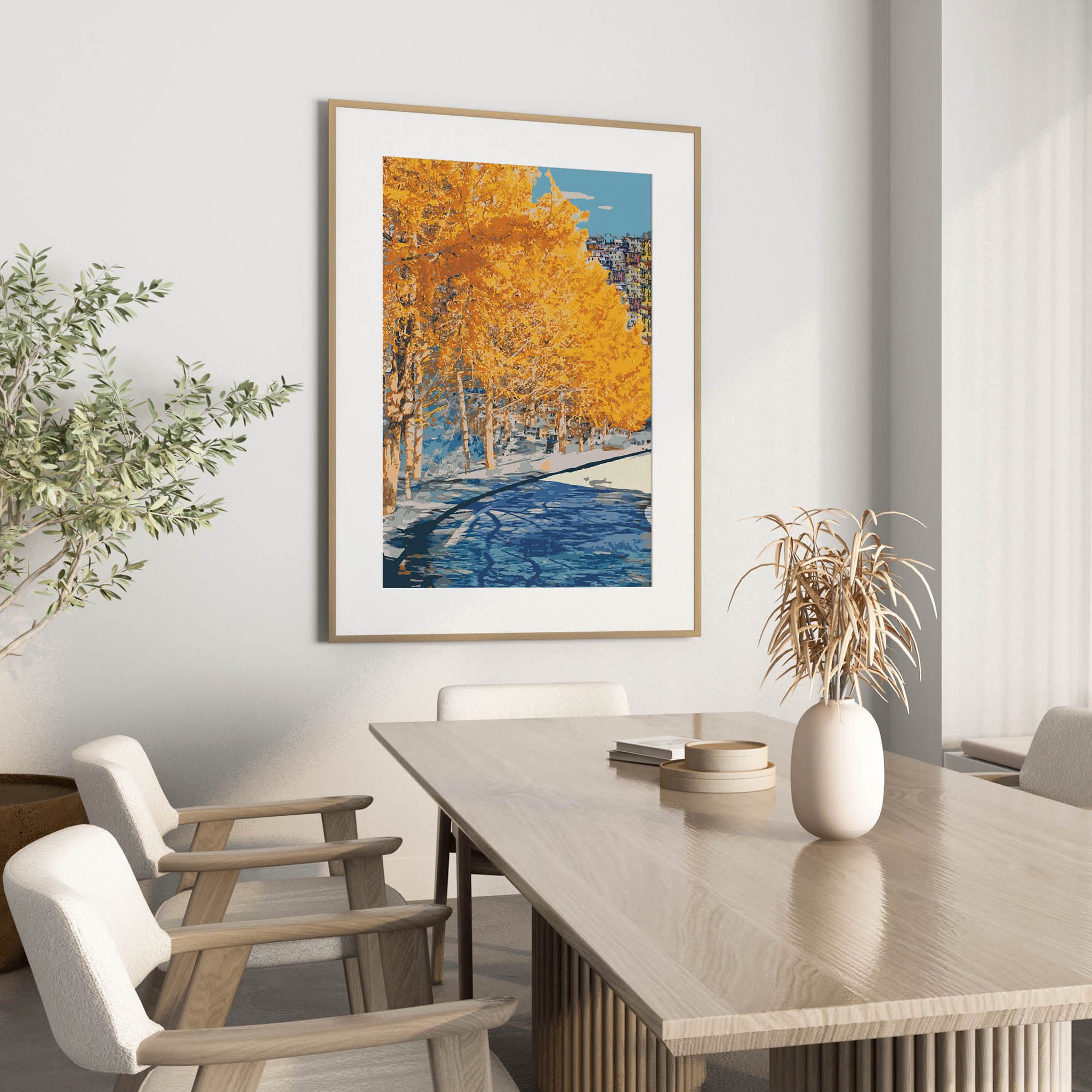 Autumn city park wall art featuring a row of golden-yellow trees along a riverbank, with reflections in the water and a hillside town in the distance under a clear blue sky