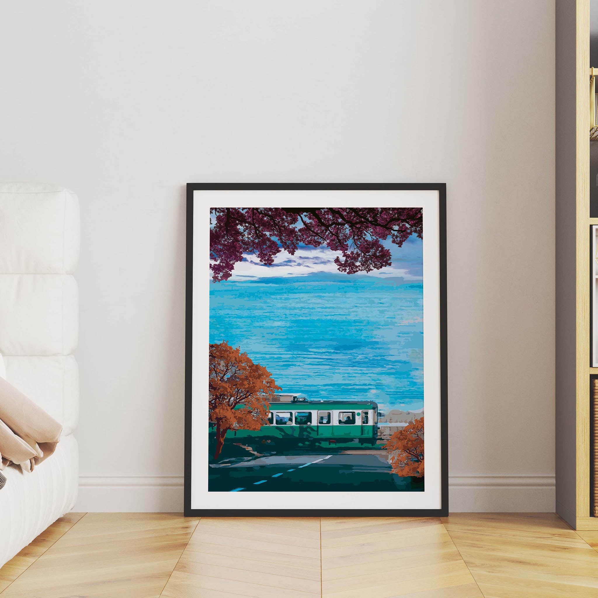 Scenic travel wall art featuring a green train passing along a coastal road lined with autumn trees, with vibrant blue ocean waves and a distant Mount Fuji under a partly cloudy sky.