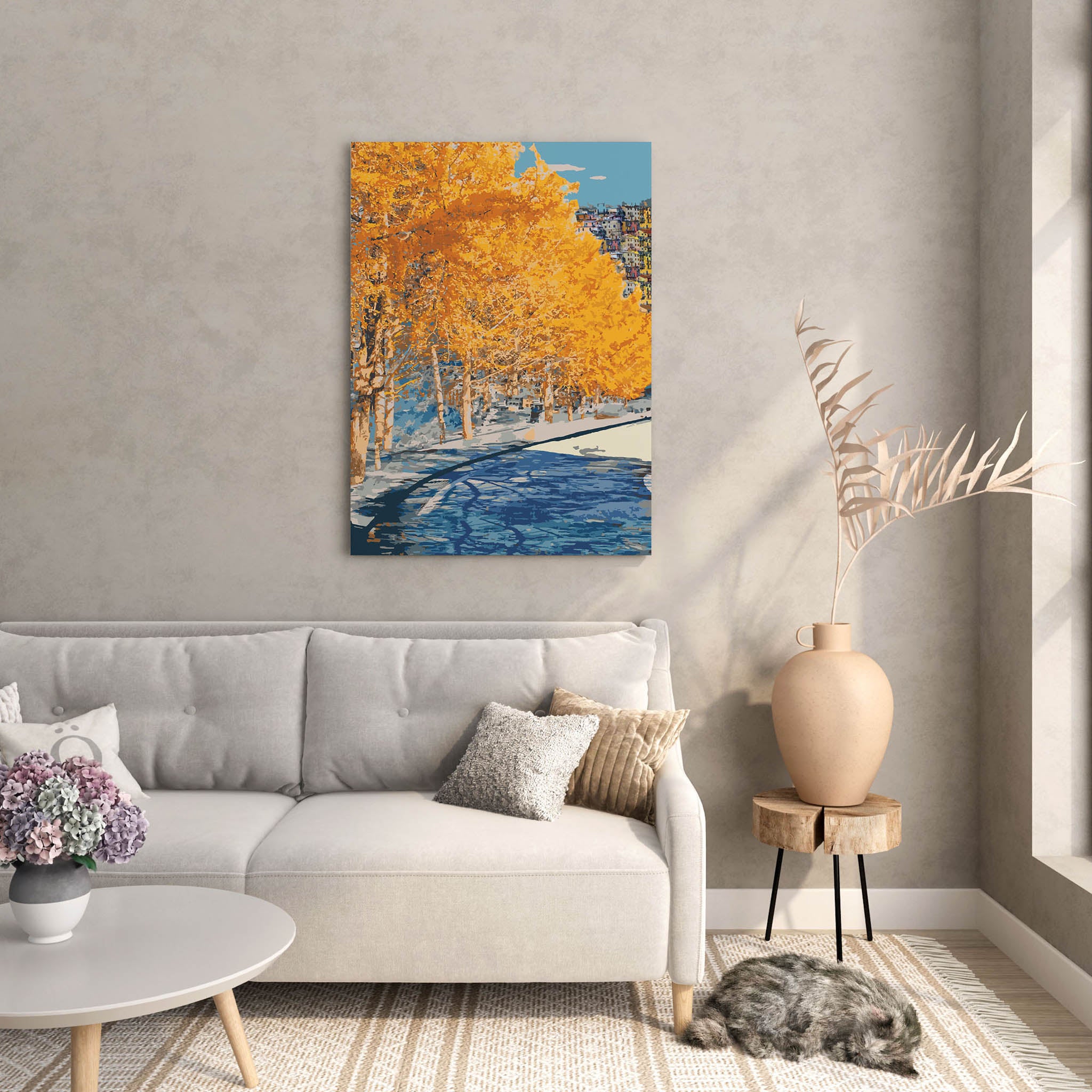 Autumn city park wall art featuring a row of golden-yellow trees along a riverbank, with reflections in the water and a hillside town in the distance under a clear blue sky