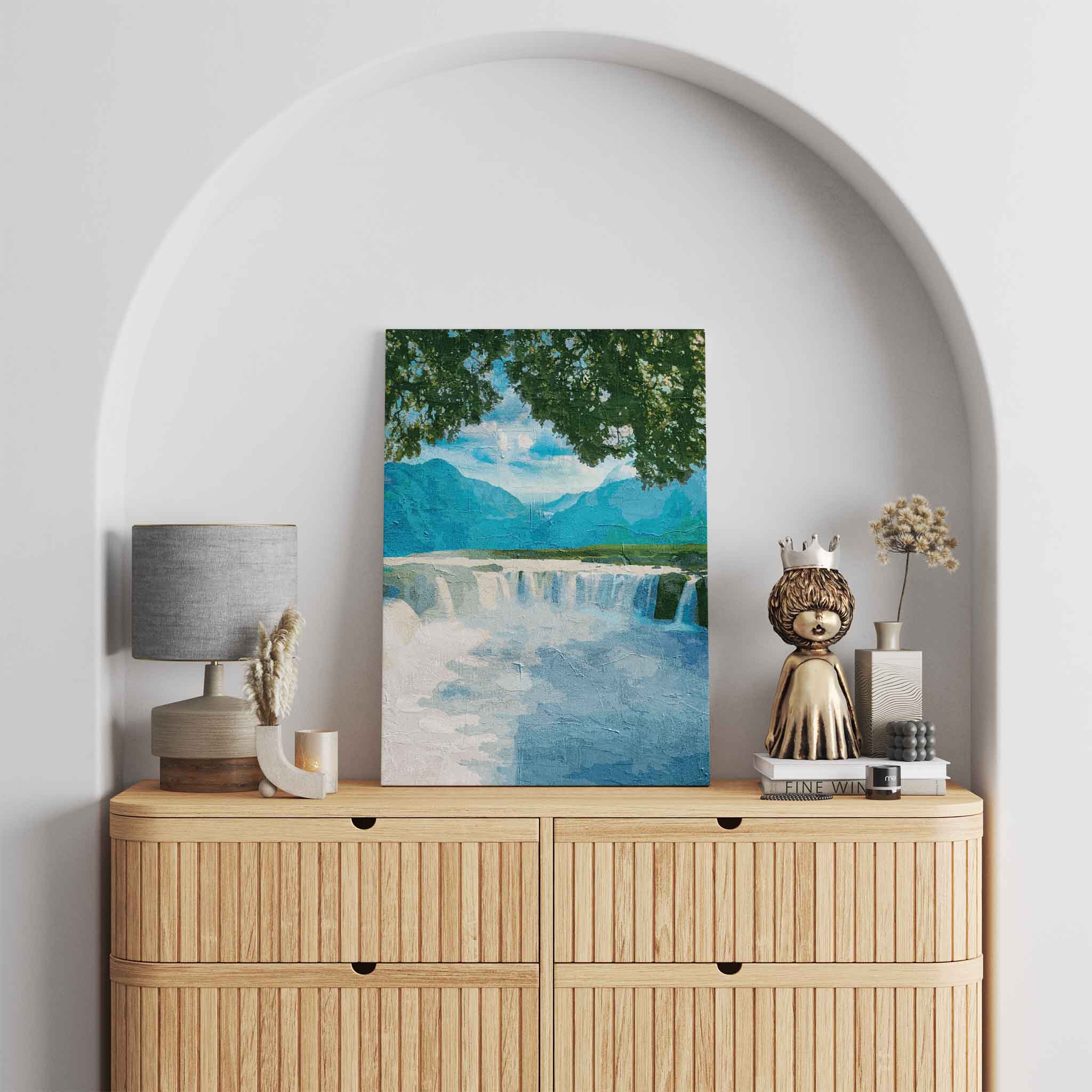 Tranquil waterfall wall art featuring a wide, gentle cascade framed by leafy tree branches, with distant blue mountains and a peaceful sky creating a calming nature scene