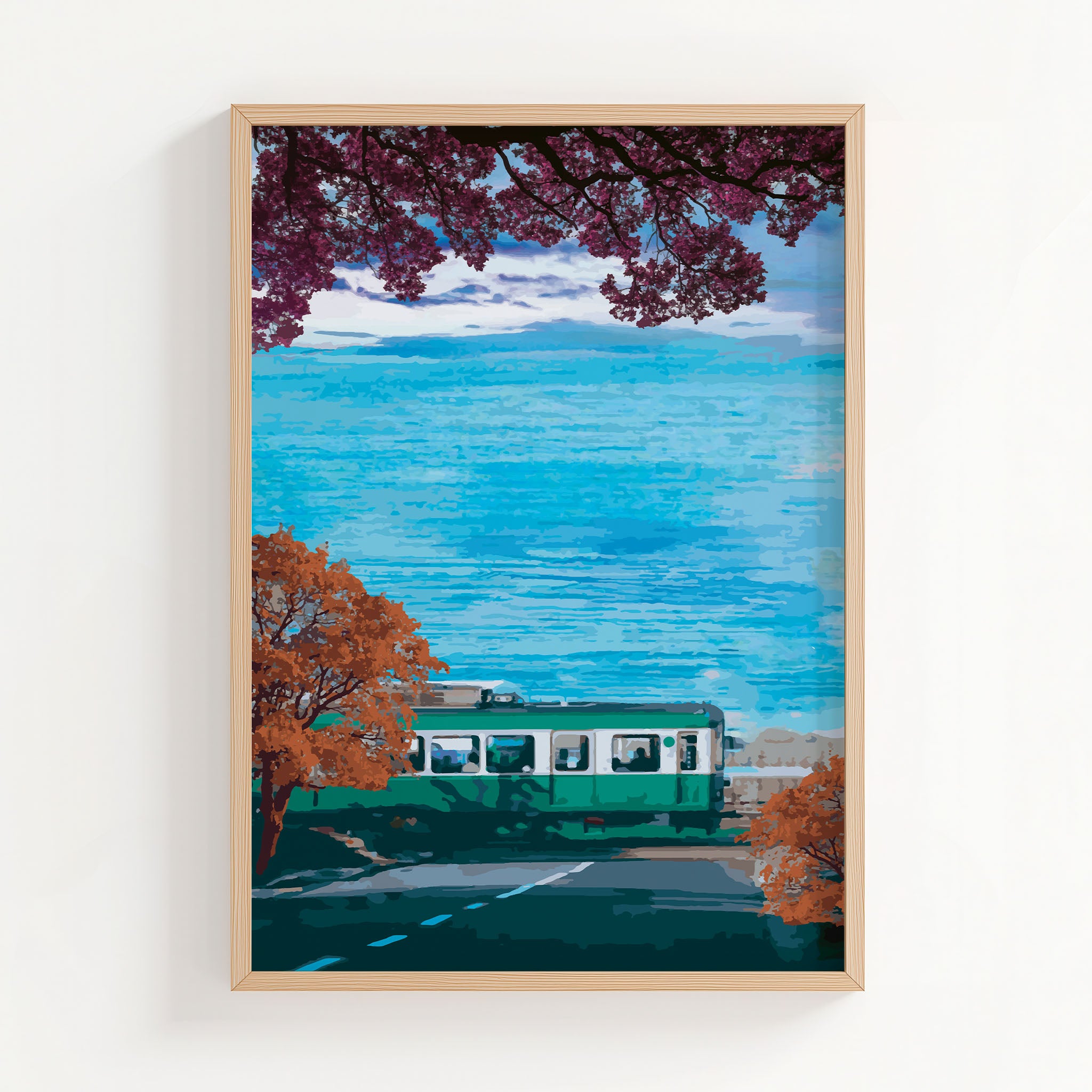 Scenic travel wall art featuring a green train passing along a coastal road lined with autumn trees, with vibrant blue ocean waves and a distant Mount Fuji under a partly cloudy sky.