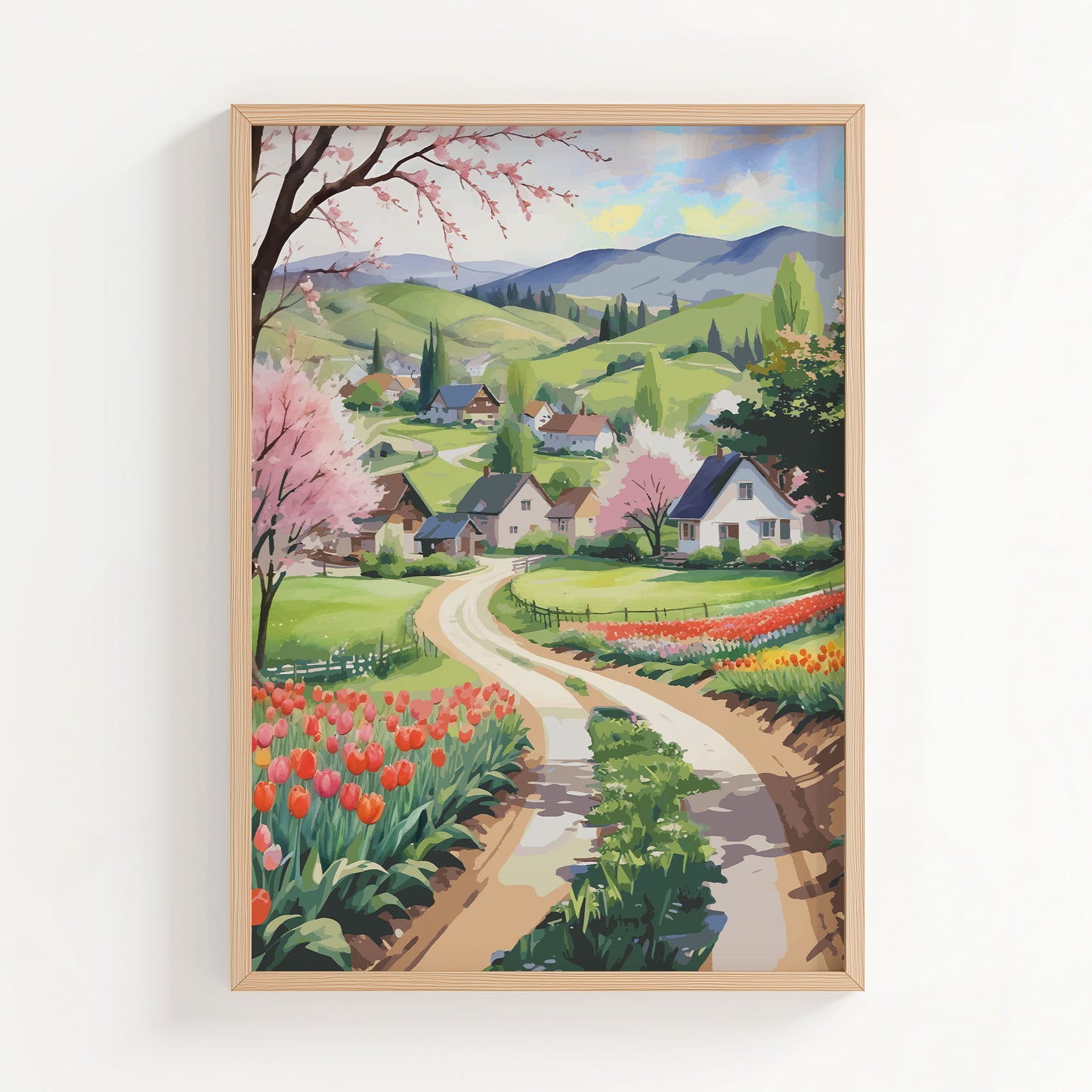 Charming countryside printable wall art showcasing a winding dirt road through vibrant tulip fields, blossoming trees, and cozy houses nestled in green rolling hills with distant mountains, perfect for spring, farmhouse, or cottagecore-inspired decor