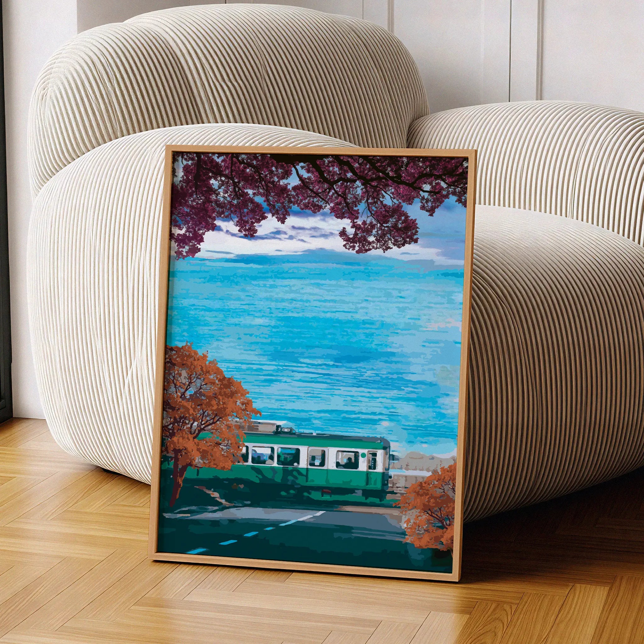 Scenic travel wall art featuring a green train passing along a coastal road lined with autumn trees, with vibrant blue ocean waves and a distant Mount Fuji under a partly cloudy sky.