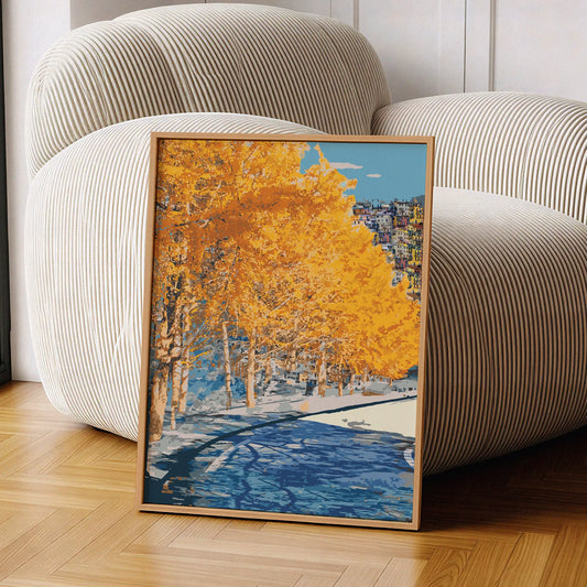 Autumn city park wall art featuring a row of golden-yellow trees along a riverbank, with reflections in the water and a hillside town in the distance under a clear blue sky
