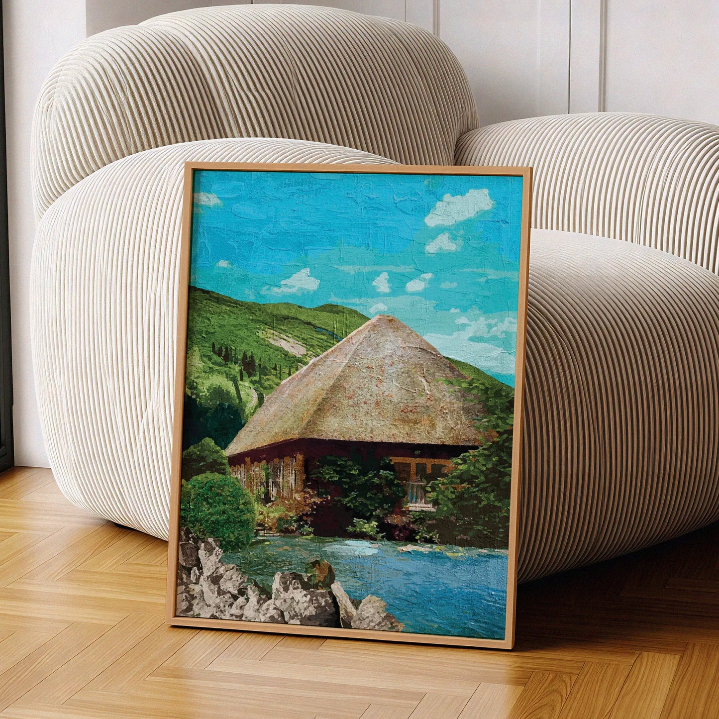 Rustic cottage wall art featuring a charming thatched-roof house surrounded by lush greenery and nestled beside a peaceful pond, with rolling green hills and a bright blue sky in the background