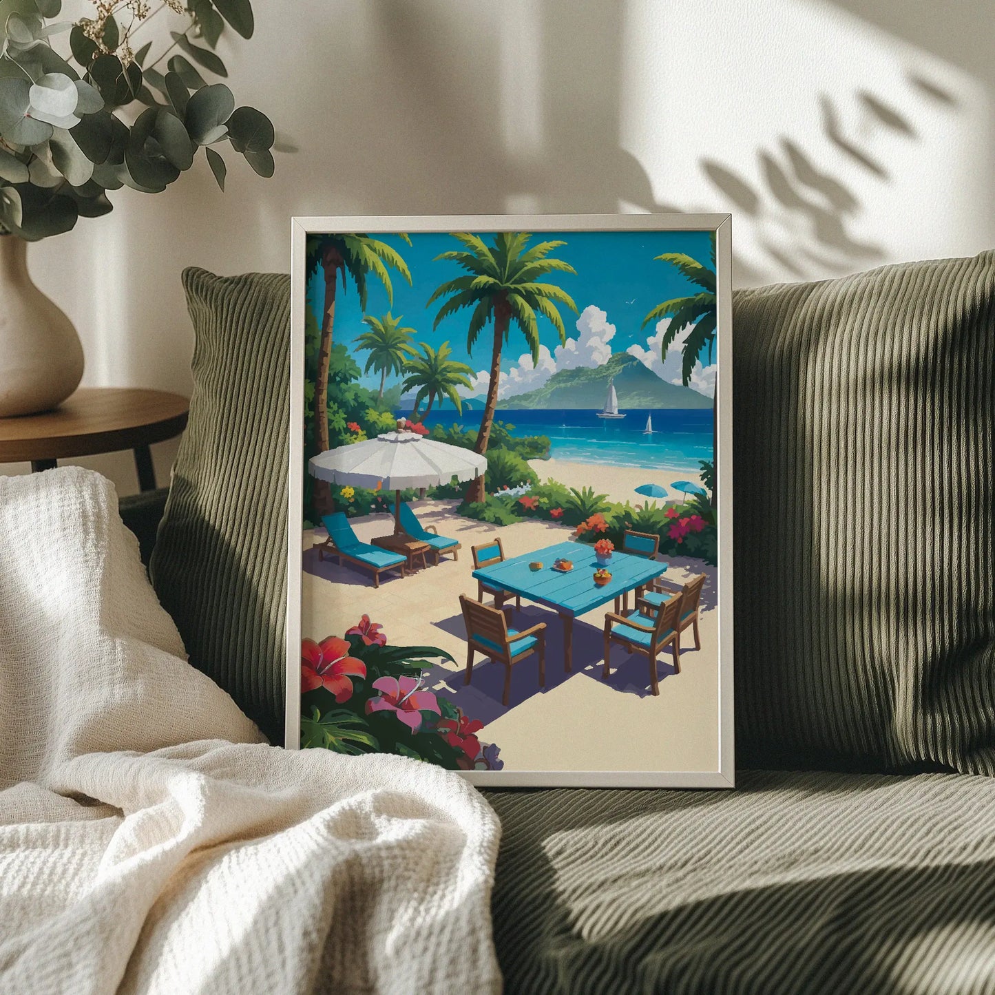 Tropical beachside printable wall art featuring a vibrant patio scene with a blue dining table, lounge chairs under a white umbrella, palm trees, colorful flowers, and sailboats on turquoise waters with a lush island in the background - perfect for summer, coastal, or vacation-themed decor