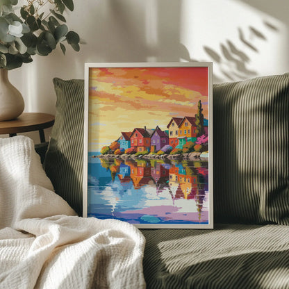 Colorful coastal village wall art featuring charming rainbow-hued houses reflected in calm water, set against a warm, golden sunset sky with vibrant orange and pink clouds