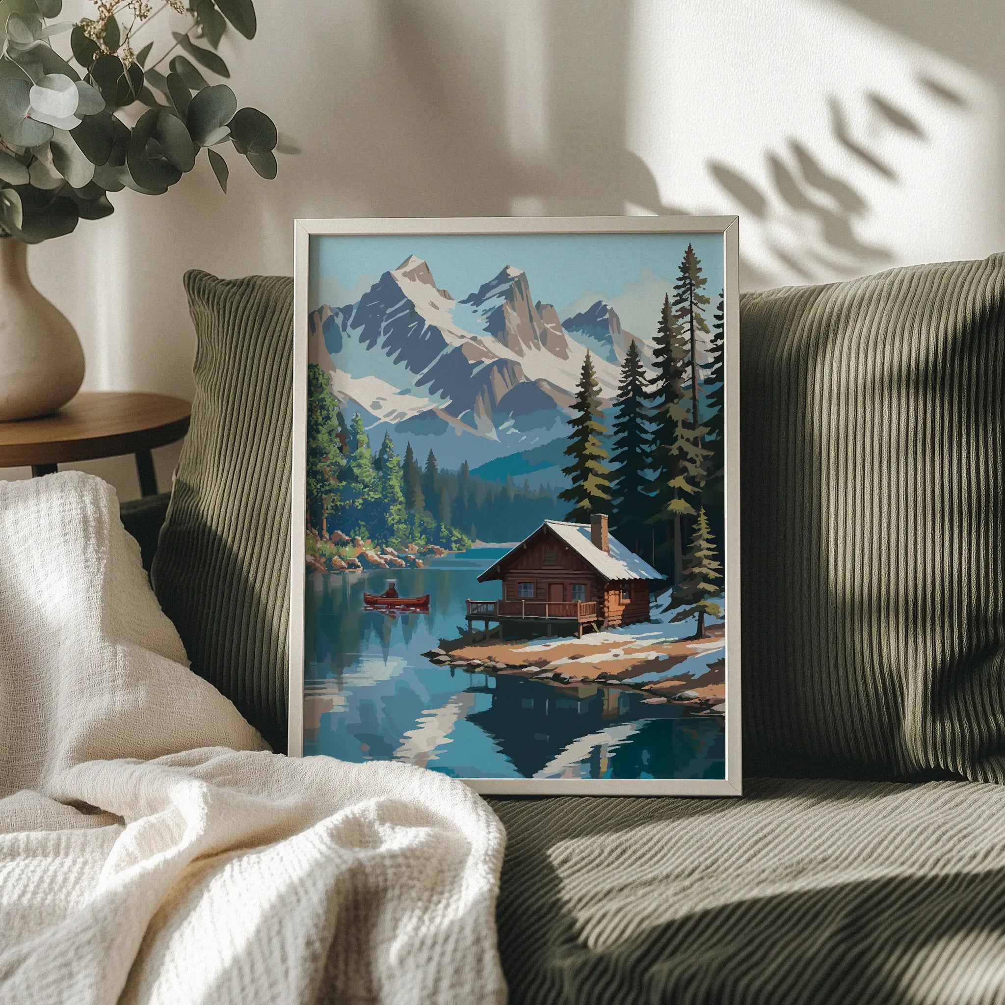 Rustic winter cabin printable wall art featuring a cozy log cabin on the edge of a tranquil lake, surrounded by snow-dusted pine trees and dramatic snow-covered mountain peaks, with a red canoe gliding across the water, perfect for cabin, adventure, or nature-inspired decor