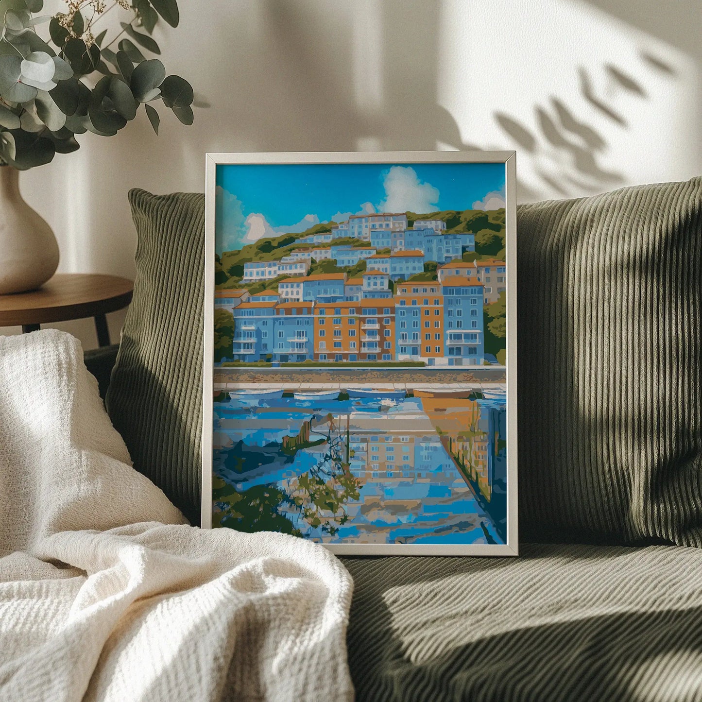 Coastal cityscape wall art showcasing colorful hillside buildings in shades of blue and orange, reflected in a calm waterfront marina with small boats and a bright blue sky overhead