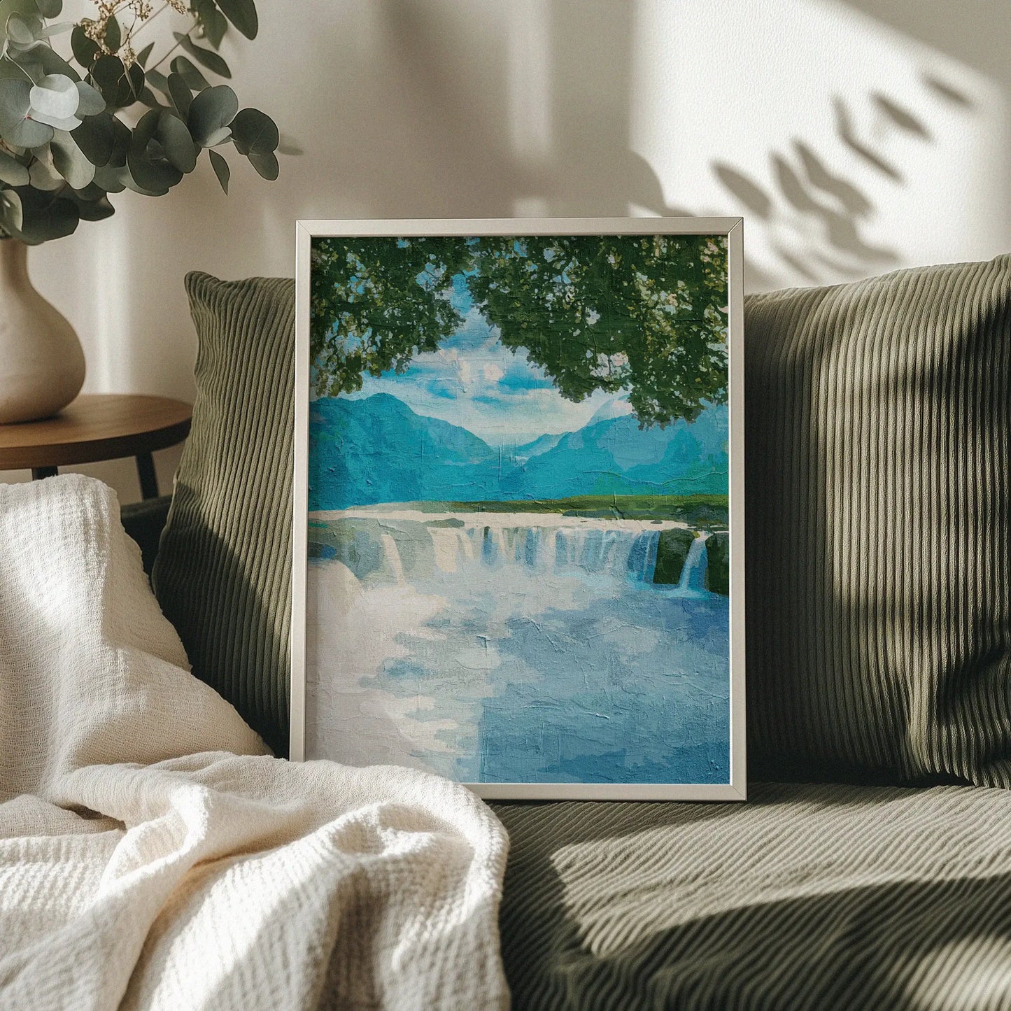 Tranquil waterfall wall art featuring a wide, gentle cascade framed by leafy tree branches, with distant blue mountains and a peaceful sky creating a calming nature scene
