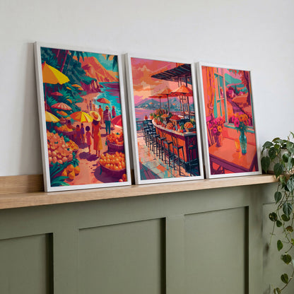 Three SweetPixelCreations travel lifestyle prints propped on a wood ledge against sage wainscoting — outdoor market, coastal bar, and interior window scenes united by a warm dopamine palette of orange, coral, teal, and magenta