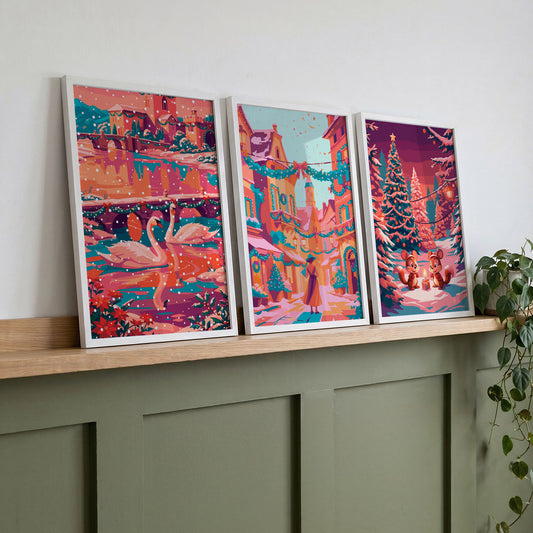 Set of three coral and teal holiday wall art prints displayed on a wooden shelf above a green console